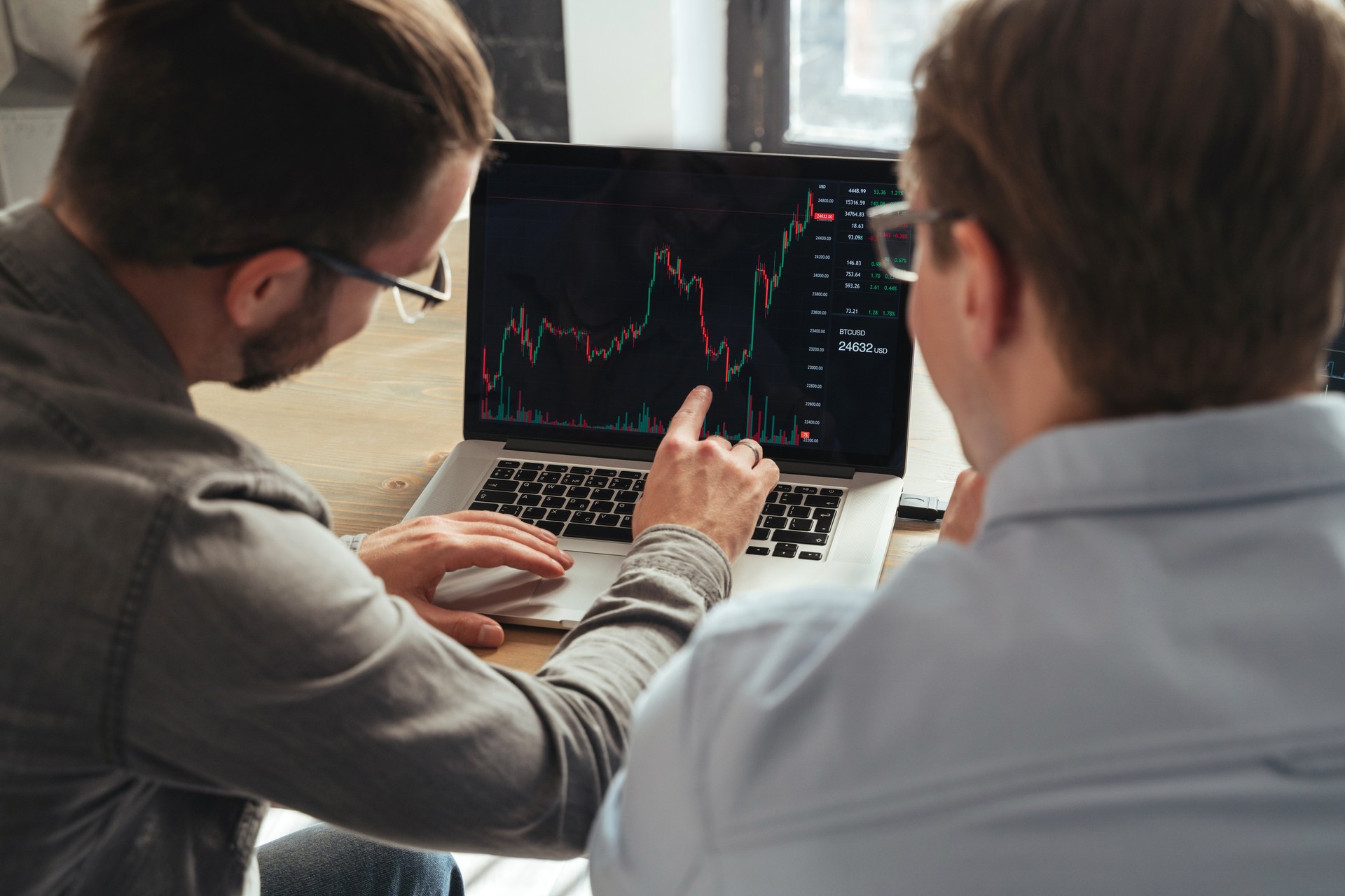 Over shoulder view of trader couch teaching another man basics of cryptocurrency investments